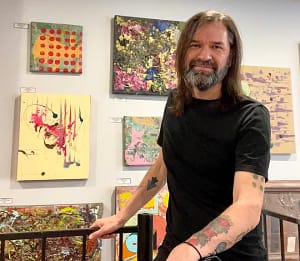 Nicholas Hall with some of his art work in his Bloomington home.